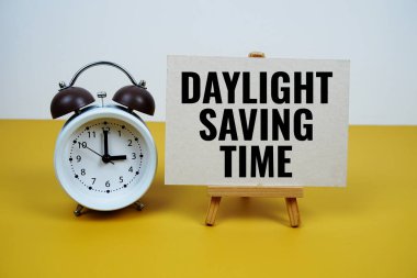Sarı zemin üzerinde alarm saati olan kağıt üzerinde gün ışığı kaydedici zaman metni