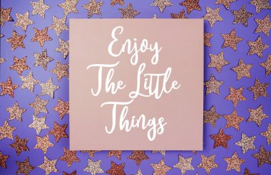 The Little Things 'in tadını çıkarın. Kağıt üzerinde motive edici ve ilham verici alıntılar, mor arka planda yıldız parıltısı dekorasyonu düz yatıyordu.