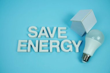 Ev modeli ve mavi arkaplanda LED ampulleri, tasarruf ve çevre dostu kavram içeren Enerji alfabesi harflerini kaydet