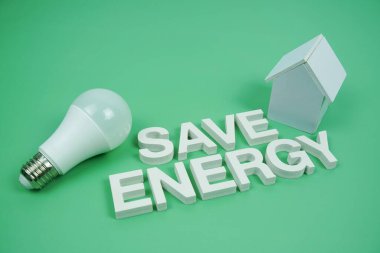 Ev modeli ve yeşil zemin üzerindeki LED ampulleri, tasarruf ve çevre dostu kavramı içeren Enerji alfabesi harflerini kaydet
