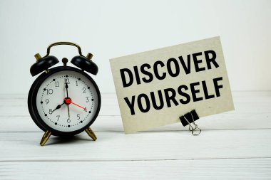 Kağıt üzerinde, ahşap zemin üzerinde alarm saati olan kendinizin metnini keşfedin