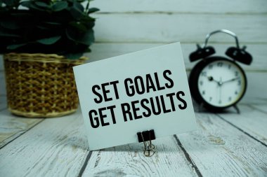 Hedefleri Tahta zemin üzerinde alarmlı saat olan kağıt kart üzerinden sonuç metni al