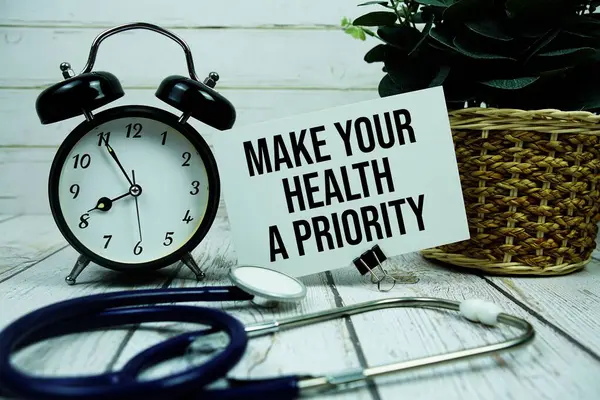 Kağıt üzerinde steteskop ve ahşap arka planda alarm saatiyle Sağlığınıza Öncelikli Mesaj Yapın