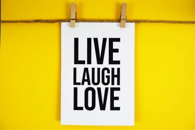 Sarı arkaplanda kağıt üzerinde Live Laugh Love metni