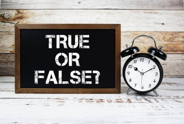 Doğru mu, yanlış mı? Tahta arkaplanda metin mesajı ve alarm saati