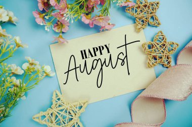 Kumaş kurdeleli kağıt kart ve mavi arkaplanlı rattan yıldız dekorasyonlu Ağustos ayınız kutlu olsun.