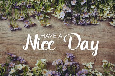 Ahşap arka planda çiçek süslemesi olan iyi günler mesajı olsun.