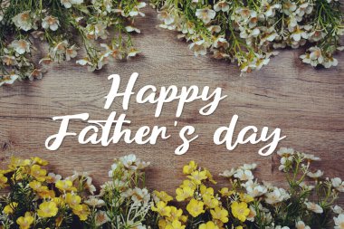 Babalar Günü mesajınız kutlu olsun. Ahşap arka planda çiçek süslemesi var.