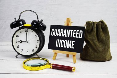 Alarm saati ve ahşap arka planda büyüteç içeren garantili gelir metni