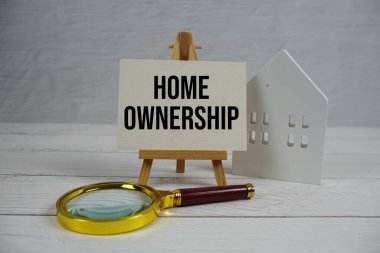 Beyaz Saray modeli ve ahşap arka planda büyüteçle ev sahipliği metni