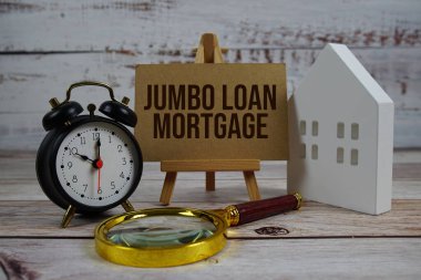 Kağıt üzerinde büyüteç, beyaz ev modeli ve ahşap arka planda alarm saati olan dev ipotek.
