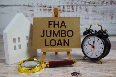 Kağıt üzerinde FHA Jumbo kredisi, büyüteç, beyaz ev modeli ve ahşap arka planda çalar saat.