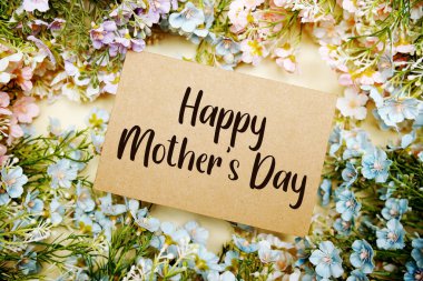 Sarı arka planda çiçek desenli kağıt üzerinde anneler günün kutlu olsun.