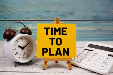 Kağıt kartla yazılmış metni hesap makinesi ve alarm saati ile tahta arka planda planlama zamanı