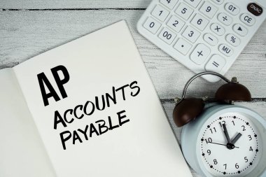 AP Ödenebilir metni kağıt defter sayfasında alarmlı saat ve tahta zemin üzerinde hesap makinesi ile hesaplar
