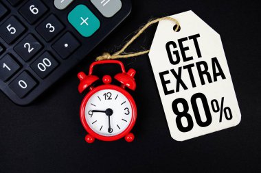 Alarmlı saat ve siyah arkaplanda hesap makinesi ile fiyat etiketi üzerine ekstra% 80 metin al