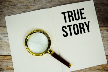 Kağıt üzerine yazılmış gerçek hikaye metni. Ahşap zemin üzerinde büyüteç görünümlü.