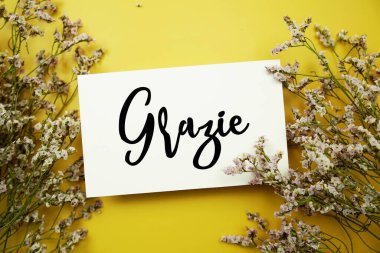 Sarı arkaplanda çiçek desenli Grazie (İtalyanca) metni