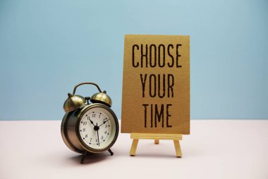 Mavi ve pembe arkaplanda sehpa ve alarmlı Zaman metninizi seçin