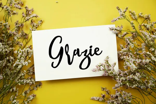 Sarı arkaplanda çiçek desenli Grazie (İtalyanca) metni