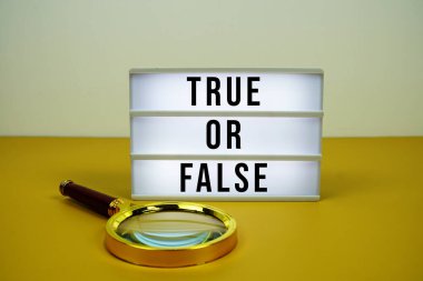 Sarı zemin üzerinde büyüteç bulunan ışık kutusu üzerindeki doğru ya da yanlış metin