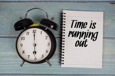 Zaman, tahta arkaplanda alarmlı saatle not defterine yazılan metni bitiriyor