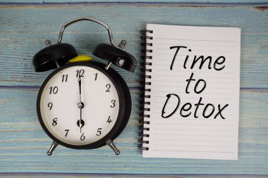 Tahta arkaplanda alarmlı saat ile birlikte not defterine yazılmış metni detoks zamanı