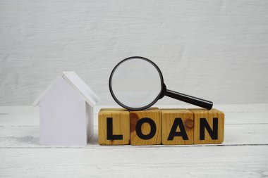 Ev modeli ve ahşap arka planda büyüteç bulunan kredi alfabesi harfleri