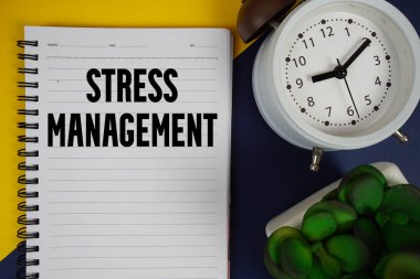 Stres Yönetimi metni not defterine yazıldı ve alarm saati mavi arkaplanda