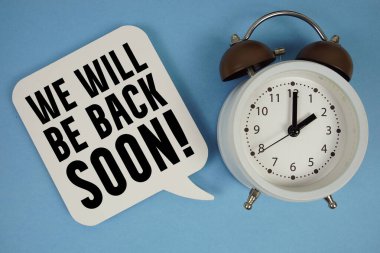 Yakında döneriz! Mavi arkaplanda alarm saati olan metin