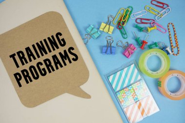 Kapak defteri arka planında kırtasiye malzemesi olan Eğitim Programları metni