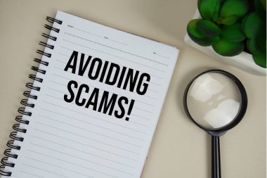 Dolandırıcılıktan kaçınmak! Kağıt not defterine bej deri arka planda büyüteç içeren metin