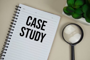 Kağıt not defterinde bej deri arka planda büyüteç bulunan dosya çalışması metni