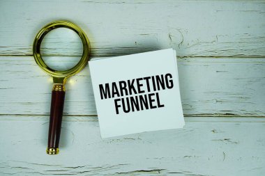 Kağıt üzerinde pazarlama hunisi metin mesajı ve ahşap arka planda büyüteç