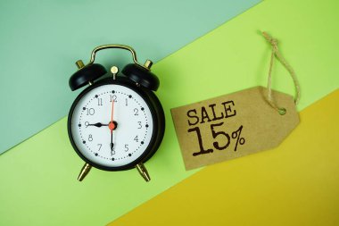 Alarmlı fiyat etiketi ve yeşil, sarı geometrik arka planda tramvay alışveriş arabası üzerine% 15 metin