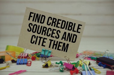 Güvenilir Kaynakları Bul ve Ahşap zemin üzerinde sabit duran kağıt kartla onlara atıfta bulun