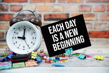 Her gün yeni bir başlangıç metni. Kağıt üzerinde alarm saati ve ahşap zemin üzerinde sabit.