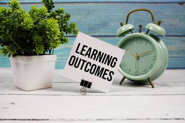 Kağıt kartla yazılmış sonuçlar metni ve ahşap zemin üzerindeki alarm saati öğreniliyor