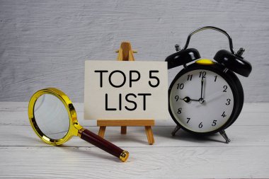 Alarm saati ve tahta zemin üzerinde büyüteç bulunan ilk 5 Liste metni