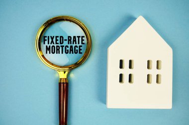 Ev modeli ve mavi zemin üzerindeki büyüteçle sabit faizli ipotek