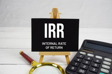 IRR Geri Dönüş Metni Büyüteç ve hesap makinesiyle ahşap zemin üzerinde.