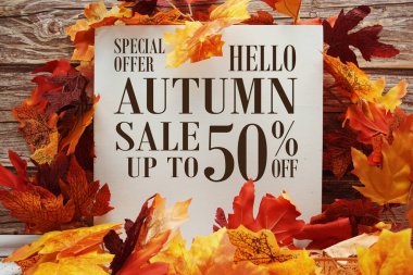 Sonbahar indirimi% 50 indirimli metin ve ahşap arka planda akçaağaç yaprağı süslemesi