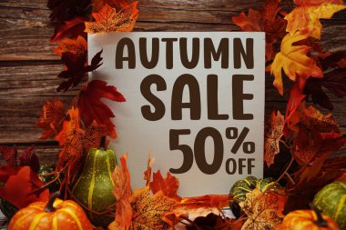 Sonbahar indirimi% 50 indirimli metin ve ahşap arka planda akçaağaç yaprağı süslemesi