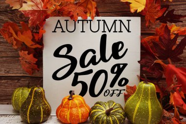 Sonbahar indirimi% 50 indirimli metin ve ahşap arka planda akçaağaç yaprağı süslemesi