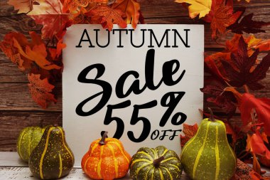 Sonbahar İndirimi% 55 indirimli metin ve ahşap arka planda akçaağaç yaprağı süslemesi