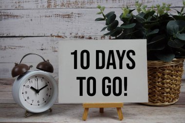 10 Days To Go text with alarm clock on wooden background
