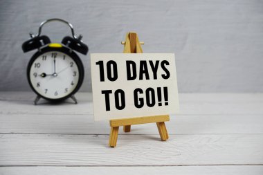 10 Days To Go! text with easel and alarm clock on wooden background