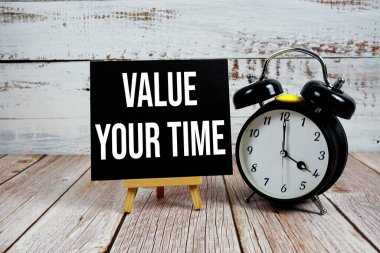 Ahşap zemin üzerinde sehpa ve alarm saati ile Zaman metninize değer verin