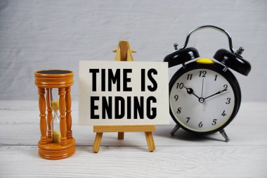 Zaman, ahşap zemin üzerinde kum saati ve alarm saatiyle metni bitiriyor