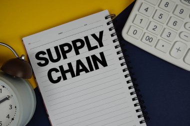 Not defterine, hesap makinesi ve lacivert zemin üzerindeki alarm saati ile yazılmış tedarik zinciri metni